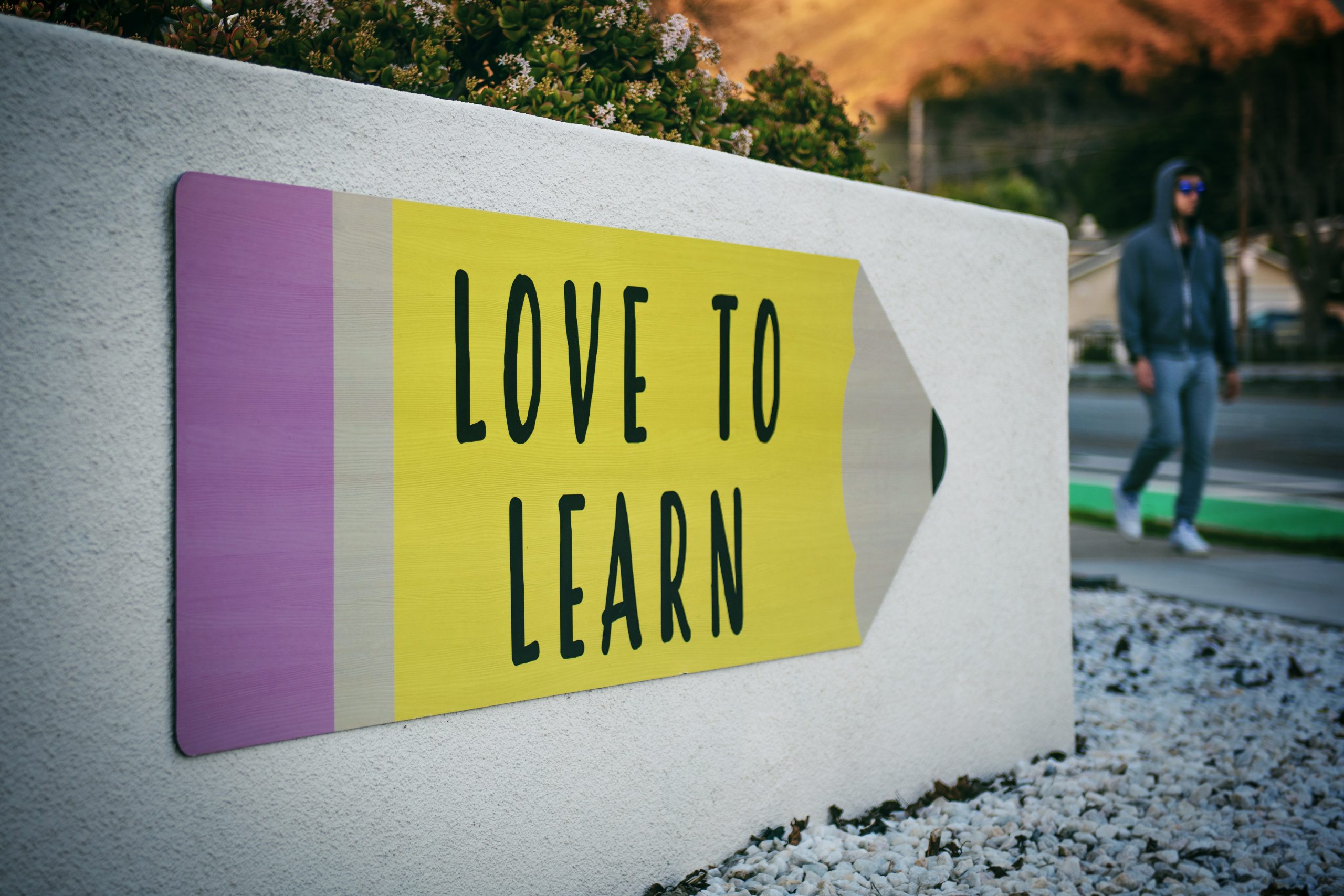 a sign in the shape of a pencil displaying the text love to learn